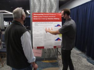 Two men look at a large poster.