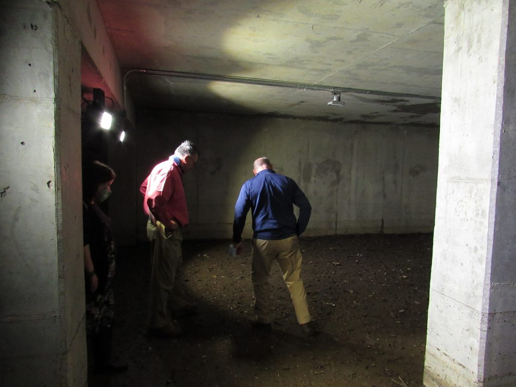 Two men standing in a concrete room.